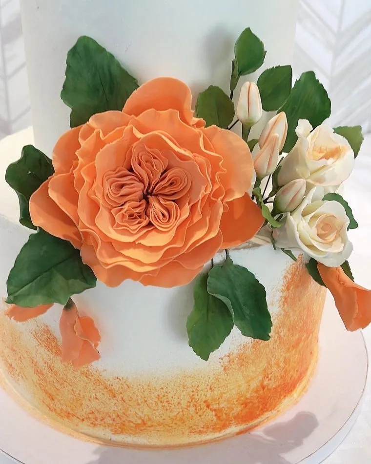 White tiered cake with a peach sugar garden rose and buds
