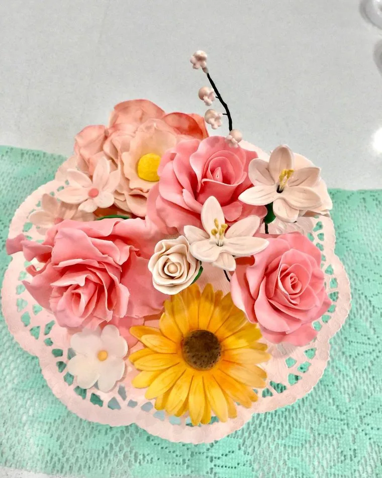 Handmade sugar flowers: pink roses, a sunflower, cherry blossom and lilies