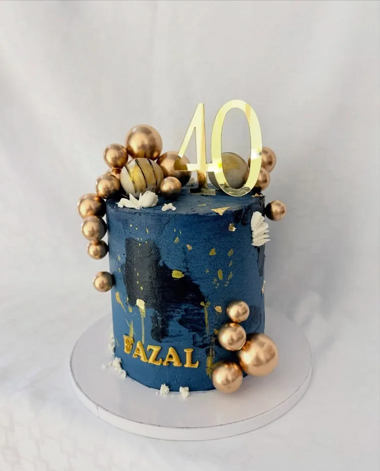 Tall navy cake with gold leaf, gold spheres and a gold 40 topper