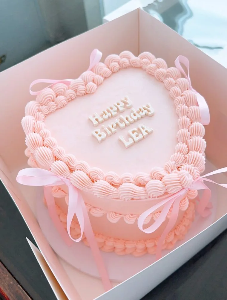 Pale pink heart-shaped cake with shell piping and satin ribbons